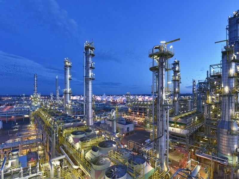 refinery - chemical factory at night with buildings, pipelines and lighting - industrial plant